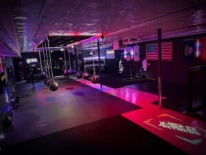 Indoor boxing gym with punching bags and neon lighting for fitness training.