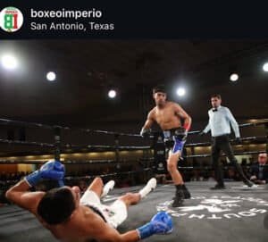Boxer delivering a punch to opponent on the ring floor during match.
