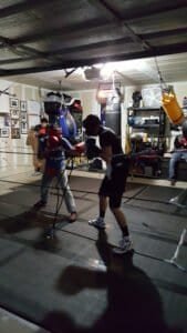 Boxers training in a boxing gym with punching bags and equipment.