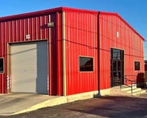 Red boxing gym building with garage door and small windows.