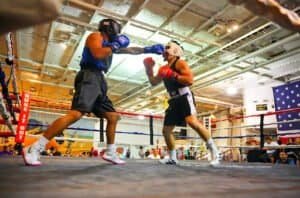 Amateur boxing match with two fighters in the ring, one throwing a punch.
