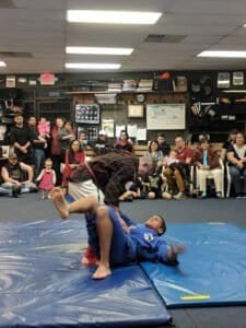Brazilian Jiu-Jitsu demonstration with two practitioners on mats.