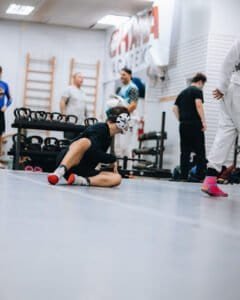 Young boxer stretching on the floor during training session at ONE Academy.