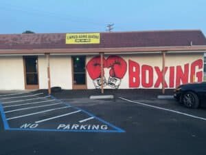 Boxing gym exterior with boxing gloves mural and signage.