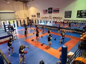 Muay Thai fighters practicing techniques in a spacious gym.