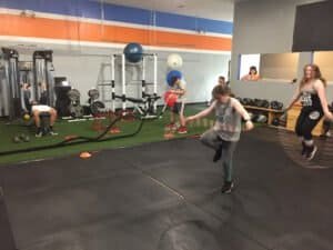 People participating in a fitness class at a boxing gym with equipment and trainers.