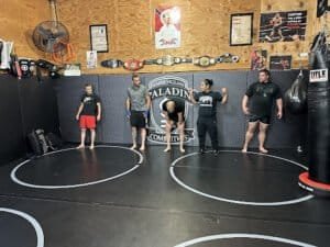 Group of fighters practicing martial arts in gym with punching bags.