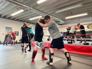 Martial arts students practicing Brazilian Jiu Jitsu and kickboxing techniques.