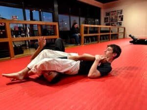 Young male practicing grappling techniques on a mat at Greenville Combatives Academy.