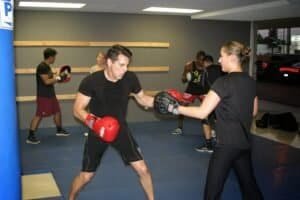 Boxing class with trainer and students practicing punches in gym.