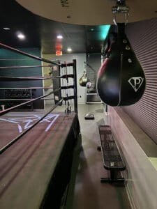 Indoor boxing gym with punching bag and boxing ring for training.