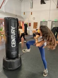 Young girl practicing kickboxing with a punching bag at MINORSAN gym.