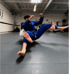 Two martial artists practicing Brazilian Jiu-Jitsu techniques in gym.