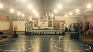 Boxing gym with ring, training equipment, and American flags.