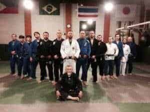 Martial arts students and instructor in dojo with flags in background.