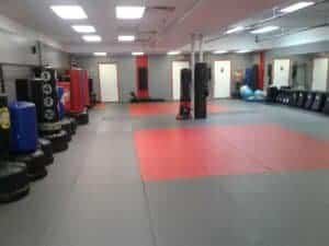 Indoor MMA gym with punching bags and training mats at Victory MMA of Selden.