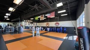 Brazilian Jiu-Jitsu practitioners training in a gym with flags and mats.