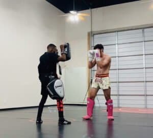 Boxer practicing punches with trainer in gym for Combat City Catch Wrestling.
