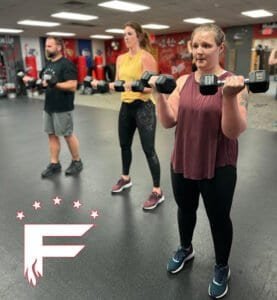Women lifting dumbbells during fitness class at FIRE Fitness Camp Shawano.