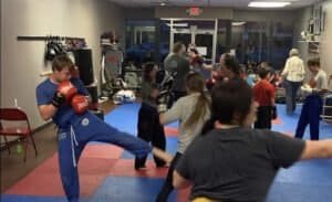 Kids and adults practicing self-defense techniques in a martial arts class.