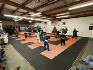 Kids and adults practicing martial arts in a training dojo.