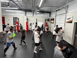 Group of people practicing boxing and kickboxing techniques in a gym.