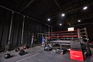 Indoor boxing gym with ring, punching bags, and workout equipment.