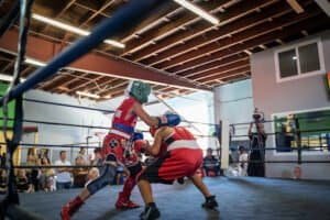 Young boxers sparring in a boxing gym with spectators watching.