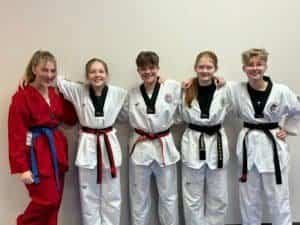 Group of kids in martial arts uniforms smiling after training session.