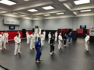 Group of students practicing Brazilian Jiu Jitsu techniques in training room.
