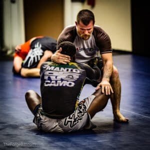 Two practitioners practicing Brazilian Jiu Jitsu techniques on mats.