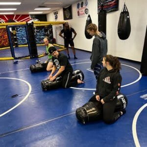 Group of students practicing boxing drills with punching bags at Evolve MMA.
