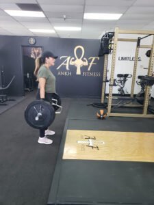 Woman performing deadlift exercise at Ankh Fitness gym.
