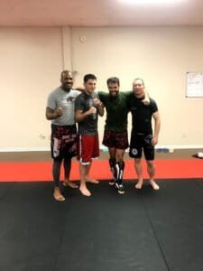Group of four men in martial arts gear at training facility.