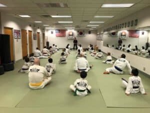 Martial arts students practicing in a dojo with American and Korean flags.