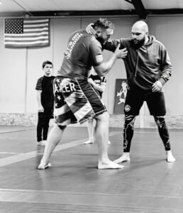 Two men practicing Brazilian Jiu-Jitsu techniques in a gym.