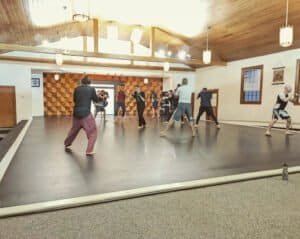 Group of people practicing kickboxing and MMA techniques indoors.