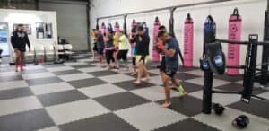 Group of people practicing boxing techniques in a gym with punching bags.