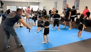 Children and instructors practicing martial arts in a training class.