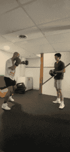 Boxer practicing punches with trainer in indoor gym at Power Within Boxing.
