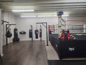 Boxing gym with punching bags and boxing ring for training.