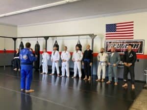 Martial arts students listening to instructor in gym with American flag.