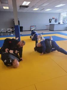 Group of practitioners practicing Brazilian Jiu Jitsu on yellow mats.