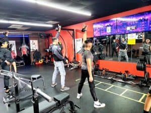Group of people practicing boxing techniques in a gym setting.
