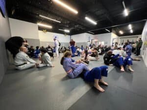 Students practicing Brazilian Jiu-Jitsu techniques in a training class.