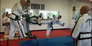 Martial arts students practicing kicks and techniques in a dojo.