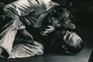 Two athletes competing in a Brazilian Jiu-Jitsu match on the mat.