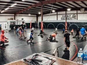 Children and adults practicing martial arts in indoor gym at Combat Athletics.