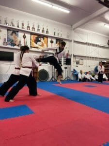 Young martial artist practicing kick with instructor at Low’s Martial Arts Academy.