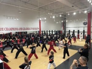Kids martial arts class practicing punches in a spacious gym.